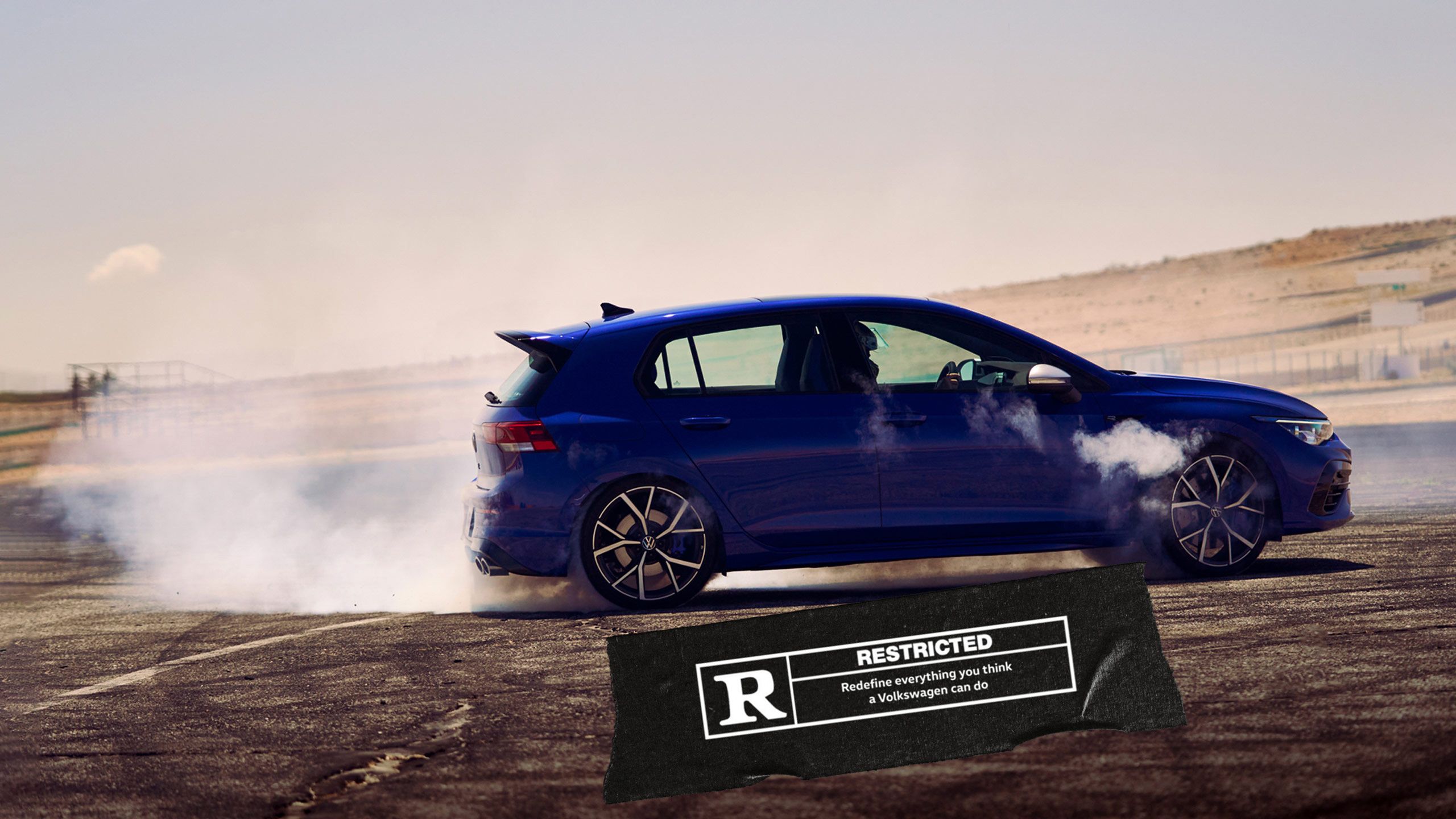Blue Volkswagen Golf R with smokes and a black label with white text
